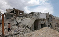 A boy stands near rubble and damaged buildings after what activists said was shelling by forces loyal to Syria's President Bashar al-Assad, in Al-Tarrab neighbourhood near Aleppo International airport May 20, 2013. REUTERS/Nour Kelze/File Photo