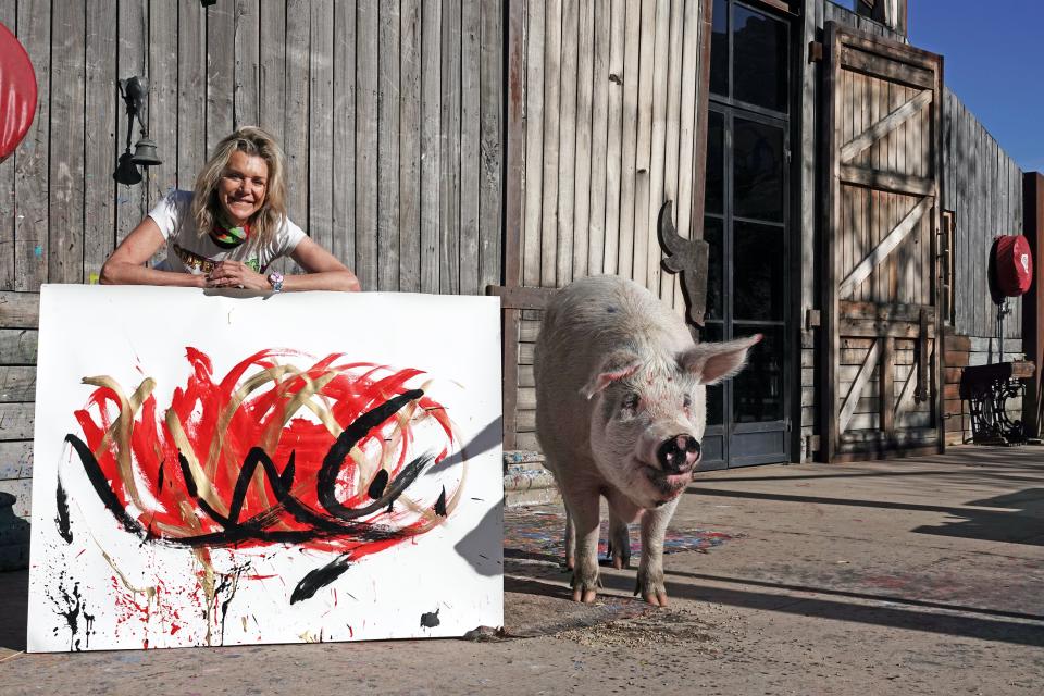 Pigcasso, a painting pig from South Africa, stands with its owner Joanne Lefson next to a picture it painted.