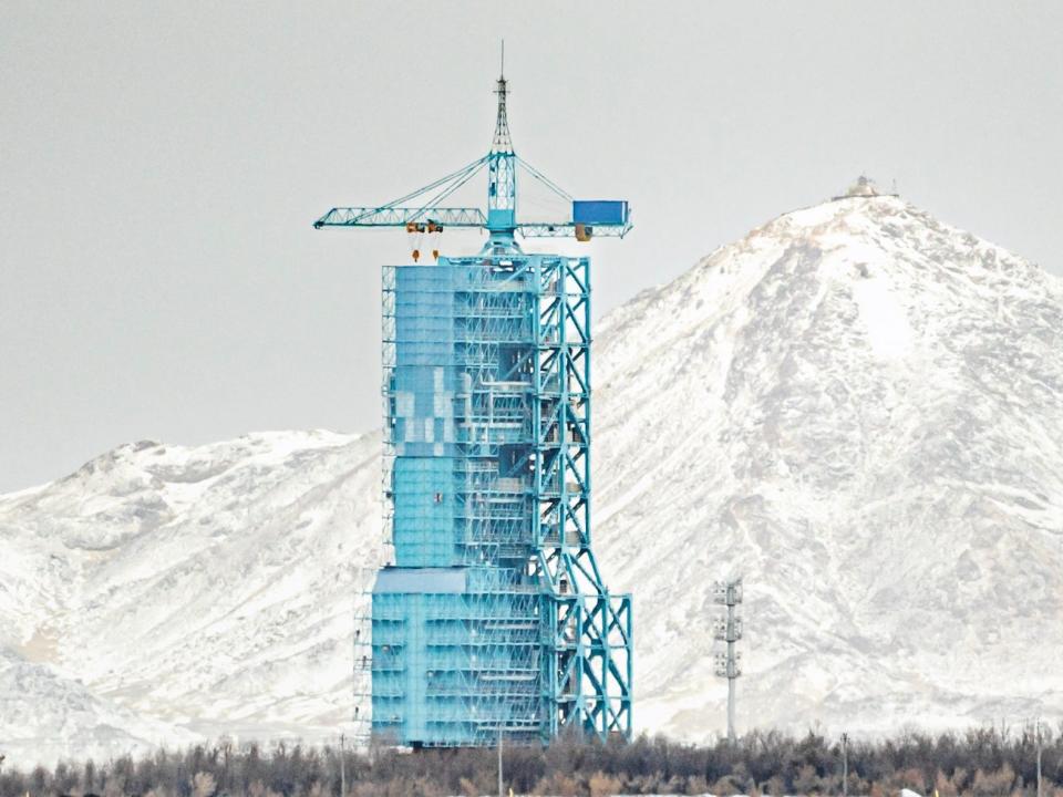 blue launch tower with rocket against white snowy mountains grey sky