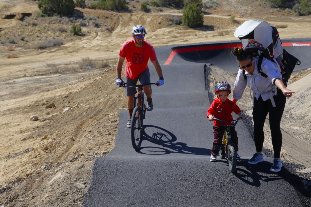 Farmington mother Tianna Blake guides her 4-year-old son Dexter Blake over a hump at the new San Juan College Bike Park Pump Track as Chris Conley watches on Wednesday, April 17.