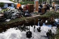 Dana Luff's brother-in-law, Michael, left, stacks items from her flooded home on the curb on Monday in the aftermath of Hurricane Ian in New Smyrna Beach, Florida.