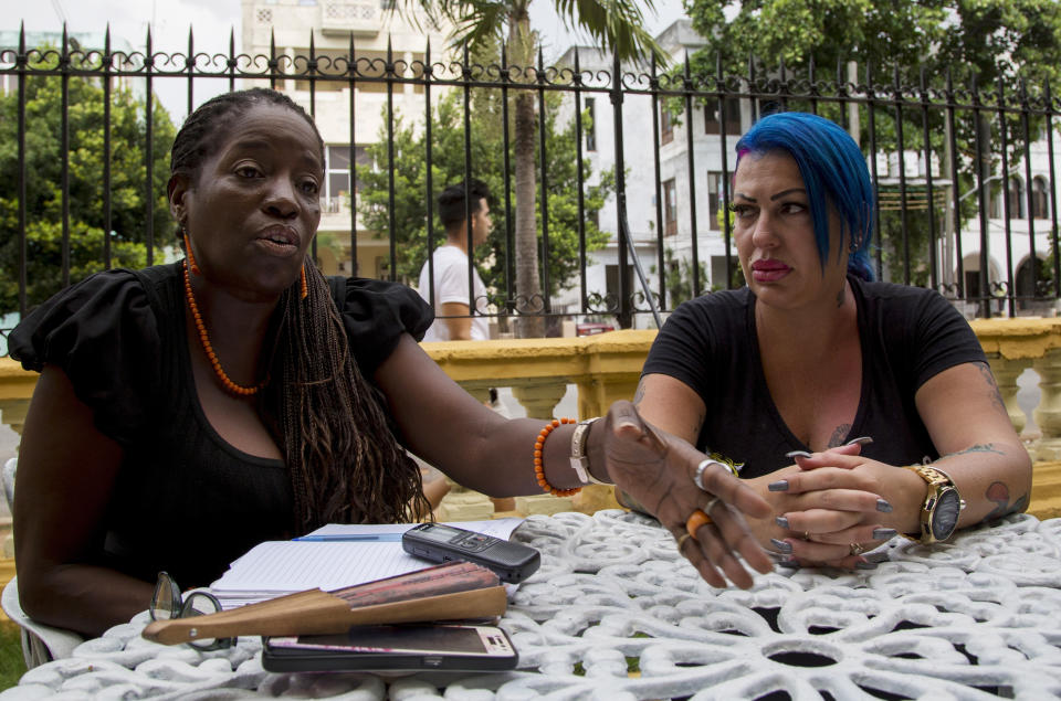 In this June 28, 2019, photo, Dianelys Alfonso, right, singer, sits with her lawyer Deyni Terry, for a photo during an interview with The Associated Press in Havana, Cuba. Alfonso publicly denounced another renowned musician, flutist and bandleader José Luis Cortés, accusing him of repeatedly hitting and raping her during her time as vocalist for NG La Banda. Terry said she and her client are still investigating whether they can bring charges of abuse and sexual assault against Cortés many years after the alleged crimes took place. (AP Photo/Ismael Francisco)