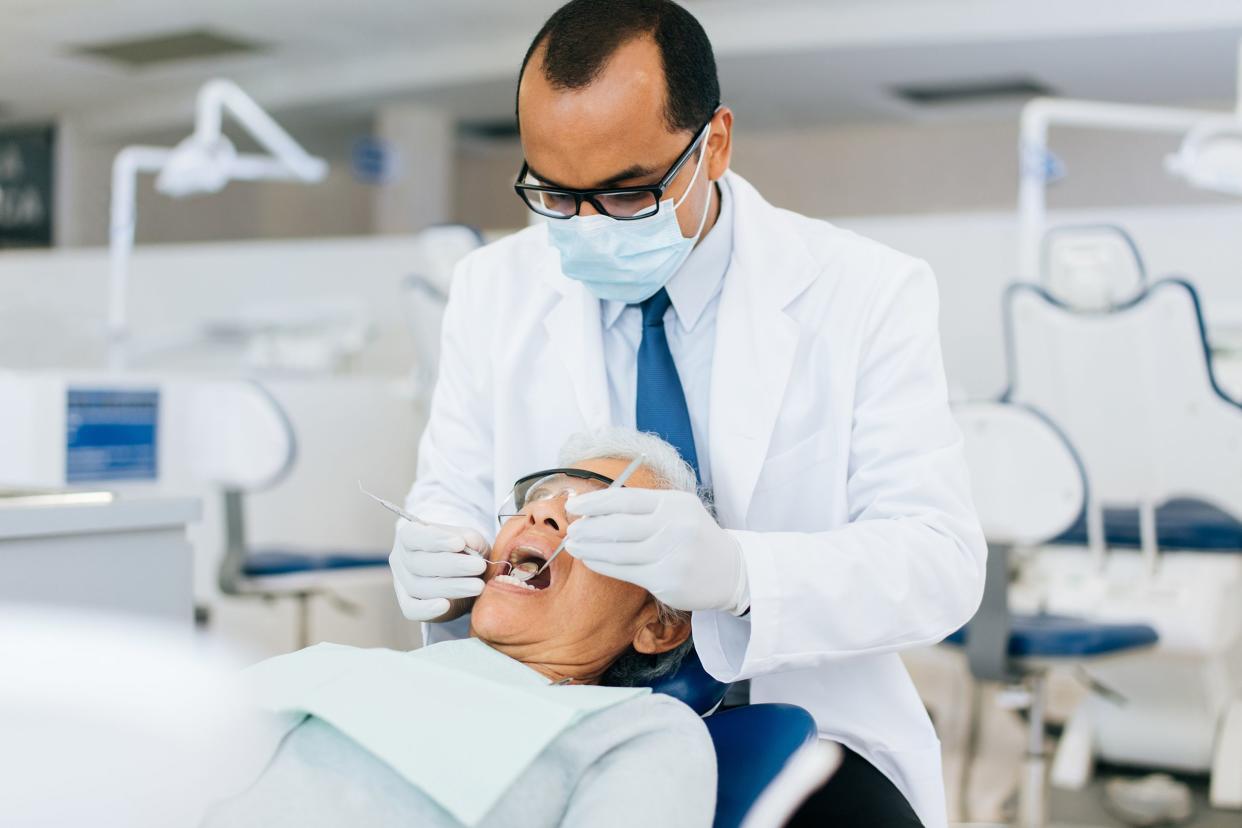 male dentist examining senior patient with instruments in Mexico