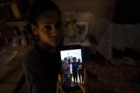 María Carla Milan Ramos shows a photo on her mobile phone of her husband with his siblings, who are all in prison accused of participating in the recent protests against the government, at their home in La Guinera neighborhood of Havana, Cuba, Wednesday, Jan. 19, 2022. Six months after surprising protests against the Cuban government, more than 50 protesters who have been charged with sedition are headed to trial and could face sentences of up to 30 years in prison. (AP Photo/Ramon Espinosa)