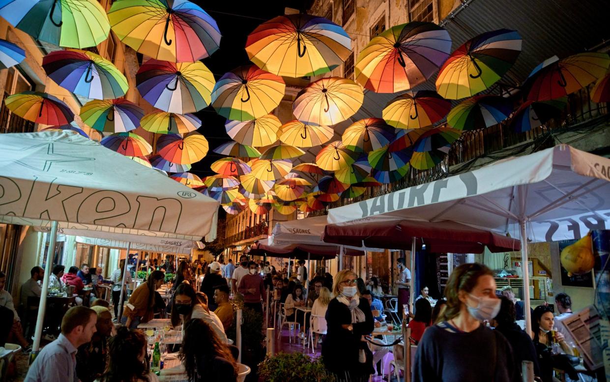 Tourists and locals sit at sidewalk tables under rainbow umbrellas in Pink Street, Cais do Sodre - Horacio Villalobos/Corbis via Getty Images