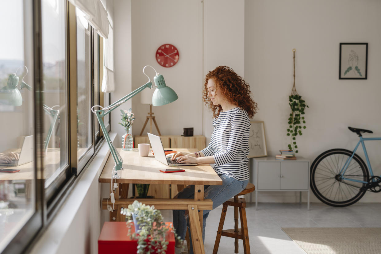 flexible working Woman sitting on a desk using a laptop computer while working from home. Business, freelance and home office concept.