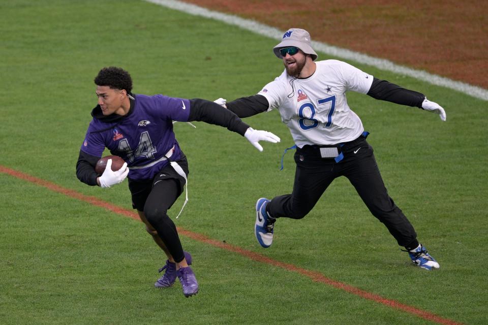 Safety Kyle Hamilton, left, of the Baltimore Ravens, runs after intercepting a pass in front of tight end Sam LaPorta (87), of the Detroit Lions, during the flag football event at the NFL Pro Bowl football game on Sunday, Feb. 4, 2024 in Orlando, Fla.