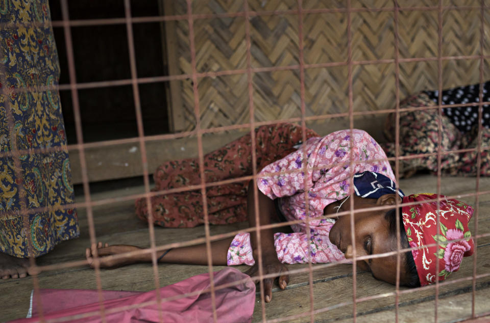 SITTWE, BURMA - MAY 06: A woman, unable to stand, lays on the porch of a makeshift clinic and pharmecy in the Thet Kae Pyin refugee camp. The medics did not know what was wrong with her specifically, but like many Rohingya she had a fever and stomach ache on May 6, 2014 in Sittwe, Burma. Some 150,000 Rohingya IDP (internally displaced people) are currently imprisoned in refugee camps outside of Sittwe in Rakhine State in Western Myanmar. Medecins Sans Frontieres (MSF), the primary supplier of medical care within the camps, was banned in March by the Myanmar government. Follow up attacks by Buddhist mobs on the homes of aid workers in Sittwe put an end to NGO operations in the camps. Though some NGOs are beginning to resume work, MSF remains banned, and little to no healthcare is being provided to most Rohingya IDPs. One Rohingya doctor is servicing 150,000 refugees with limited medication. Several Rakhine volunteer doctors sporadically enter the camps for two hours a day. Births are the most complicated procedures successfully carried out in the camps, requests to visit Yangon or Sittwe hospitals for life threatening situations require lengthy applications and are routinely denied. Malnutrition and diarrhea are the most widespread issues, but more serious diseases like tuberculosis are going untreated and could lead to the rise of drug resistant tuberculosis (DR-TB).  (Photo by Andre Malerba/Getty Images)