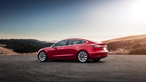 A red Model 3 at sunset