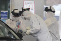 FILE - In this March 1, 2020 file photo, medical staff wearing protective suits take samples from a person with suspected symptoms of the new coronavirus at a drive-thru virus test facility in Goyang, South Korea. When the first cases of the disease showed up in South Korea, they reacted quickly with the use of widespread testing, technology to trace at-risk groups, and strict social quarantines and distancing. (AP Photo/Ahn Young-joon, File)