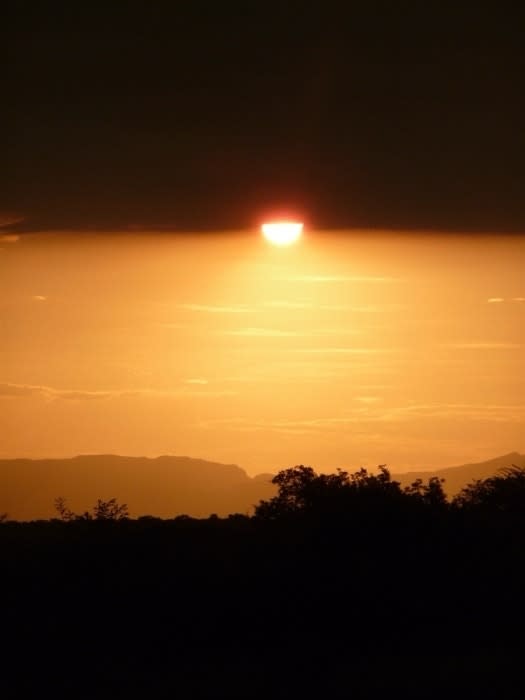 Sun setting behind hills with a bright sky indicating the end of the day