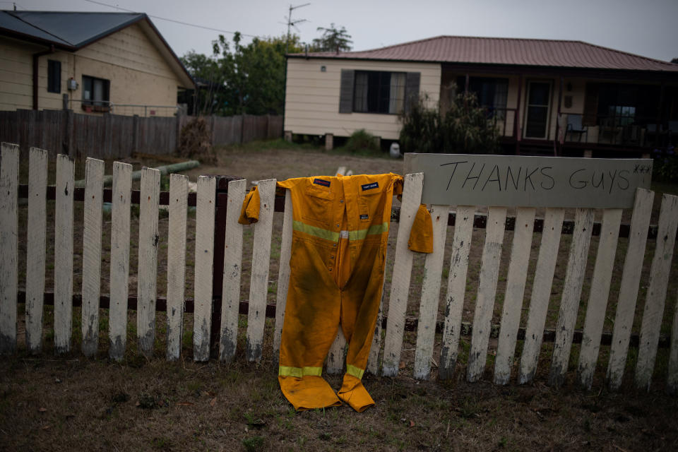 A firefighter's suit hangs on a fence next to a "Thanks guys" sign in Cobargo, New South Wales, Australia, on Jan. 12. (Photo: Alkis Konstantinidis / Reuters)