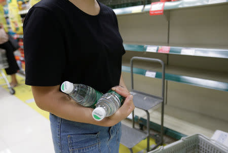 A local resident holds bottles of water at a supermarket in preparation for Typhoon Mangkhut, in Shenzhen, China September 15, 2018. REUTERS/Jason Lee