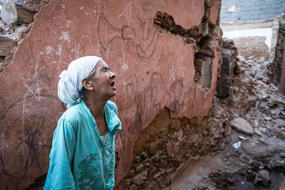 Mujer llorando en un edificación derrumbada