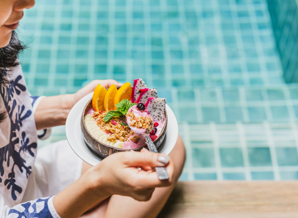 woman eating smoothie bowl by the pool to keep the weight off long-term