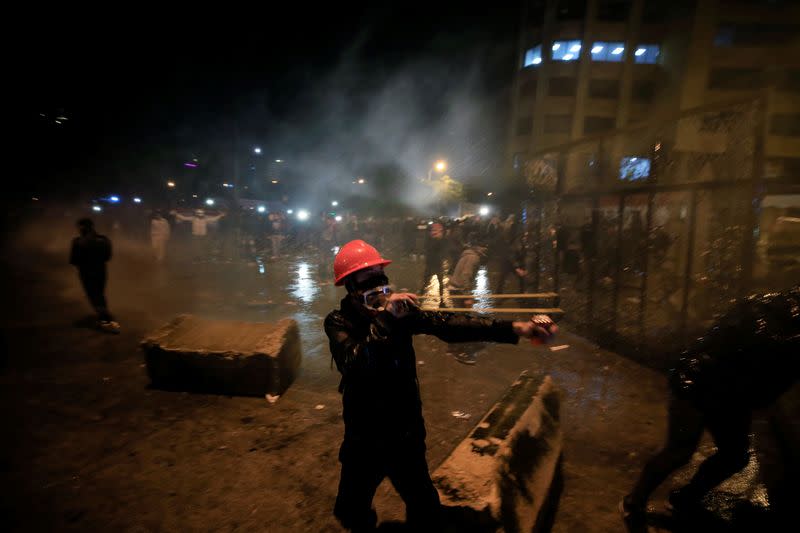 A demonstrator uses a slingshot to throw a stone during a protest against the newly formed government near the government headquarters in downtown Beirut