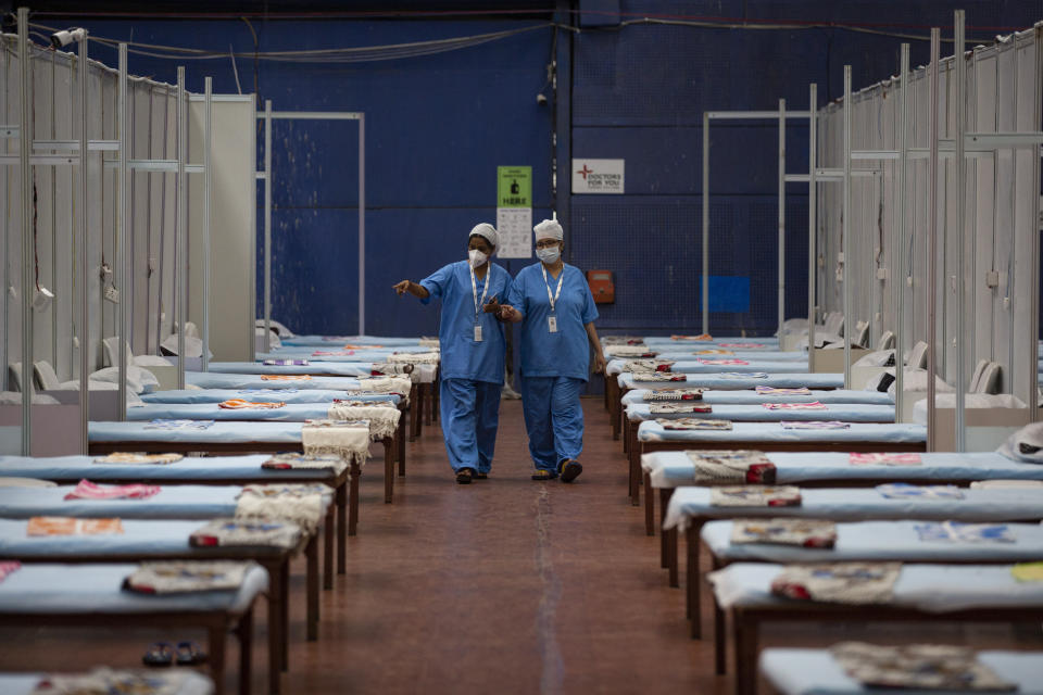 Medical staff walk past rows of beds at a makeshift COVID-19 care center at an indoor sports stadium after it was thrown open for patients in New Delhi, India, Wednesday, July 8, 2020. India has overtaken Russia to become the third worst-affected nation by the coronavirus pandemic. (AP Photo/Altaf Qadri)