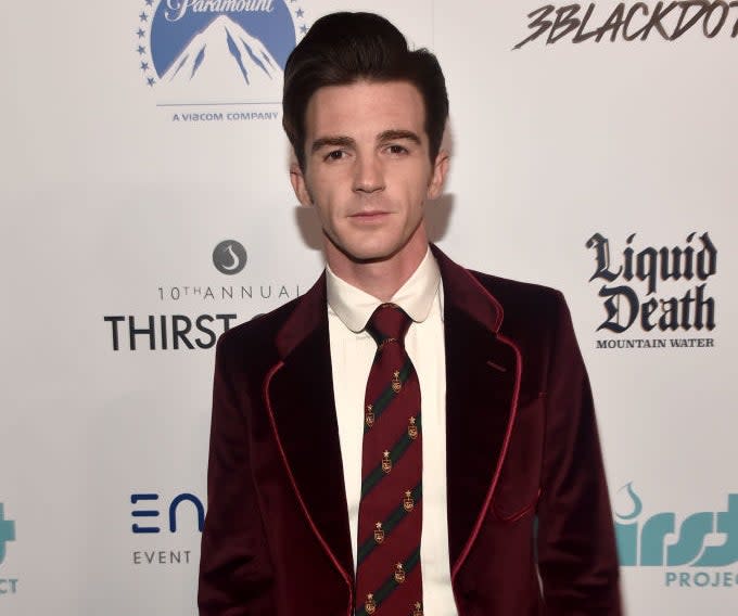 Drake Bell in a velvet suit with patterned tie, posing at an event