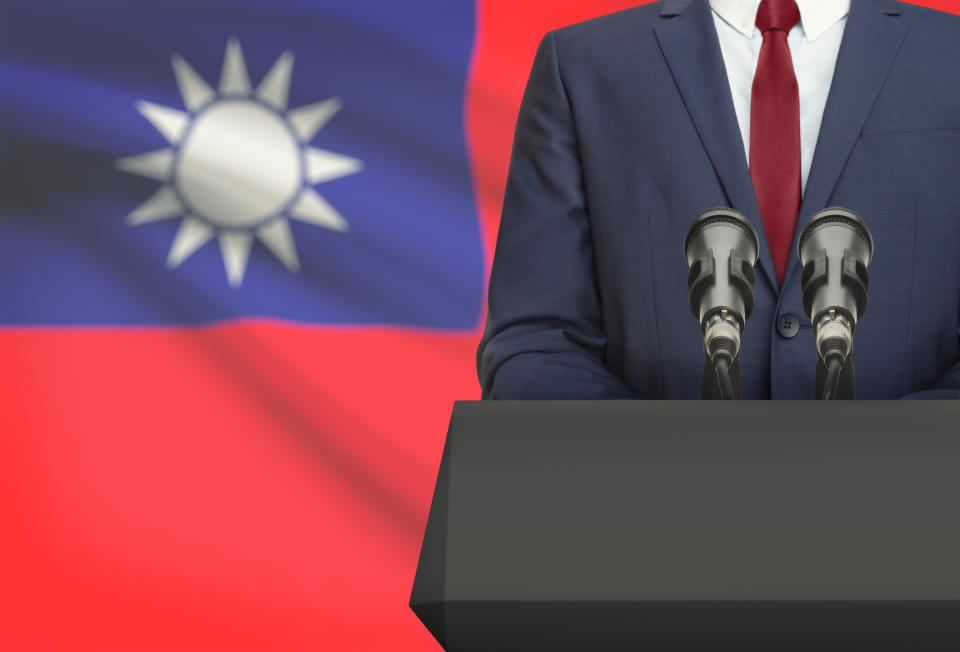 Businessman or politician making speech from behind the pulpit with national flag on background - Republic of China - Taiwan