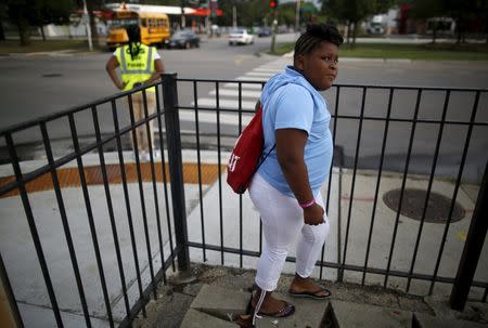 A Sherwood Elementary School student waits for Safe Passage worker Brenda Montgomery to arrange for a school bus to pick her up in the Englewood neighborhood in Chicago, Illinois, United States, September 8, 2015. REUTERS/Jim Young
