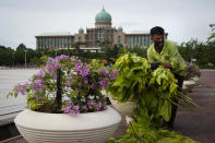 A worker cleans in front of the prime minister's office building in Putrajaya, Malaysia, Friday, Oct. 23, 2020. Malaysian opposition leader Anwar Ibrahim said Friday he was concerned about reports that Prime Minister Muhyiddin Yassi may invoke emergency laws to suspend Parliament and stymie bids to oust his government. (AP Photo/Vincent Thian)