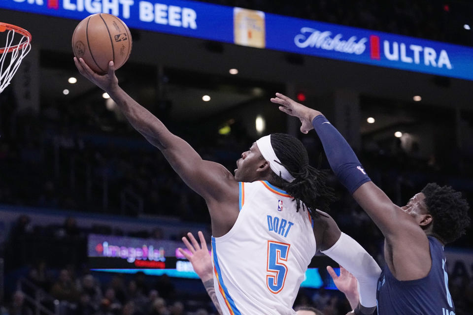 Oklahoma City Thunder guard Luguentz Dort (5) goes to the basket in front of Memphis Grizzlies forward Jaren Jackson Jr. right, in the first half of an NBA basketball game Saturday, Dec. 17, 2022, in Oklahoma City. (AP Photo/Sue Ogrocki)