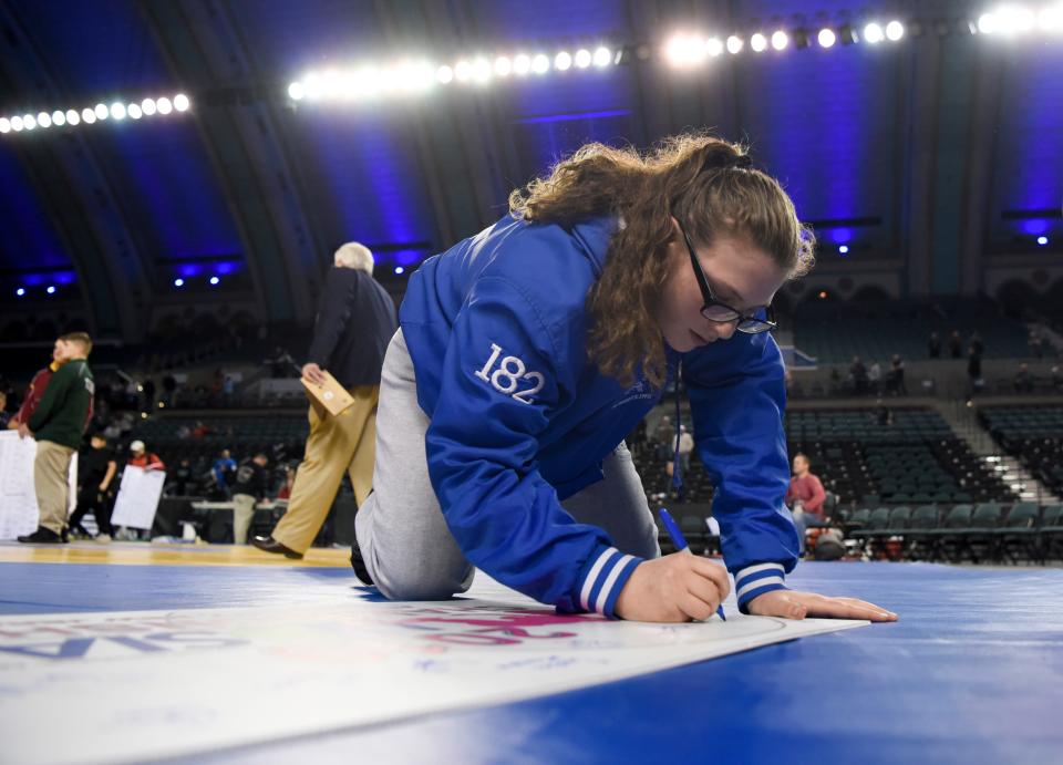 Teaneck's Erin Emery signs the NJSIAA girls wrestling tournament banner after her 185-pound title win on Saturday, March 2, 2019, in Atlantic City.