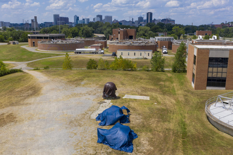 Confederate statues are covered in tarps while being stored at a waste water treatment plant near downtown Tuesday July 14, 2020, in Richmond, Va. The city of Richmond removed several of the statues along Monument Ave. where they will be stored until suitable sites can be found for them. (AP Photo/Steve Helber)