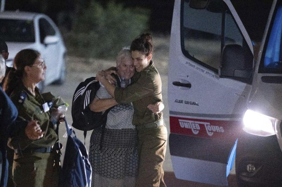 Margalit Mozes, a released Israeli hostage, walks with an Israeli soldier shortly after her arrival in Israel on Friday, Nov. 24, 2023. A four-day cease-fire in the Israel-Hamas war began in Gaza on Friday with an exchange of hostages and prisoners. (IDF via AP)