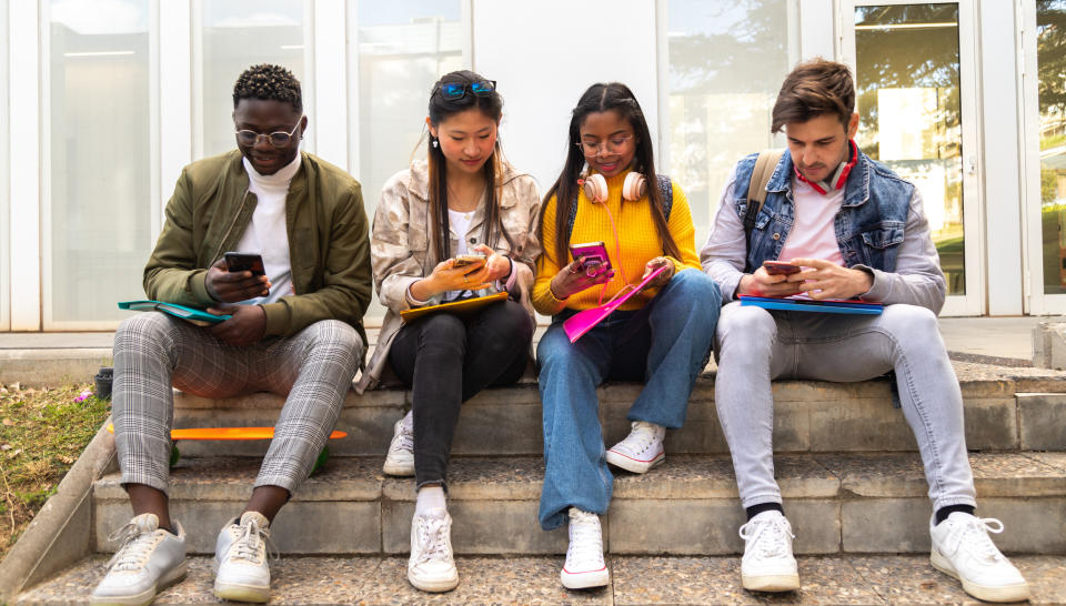 Four young people sitting on steps and looking at their phones