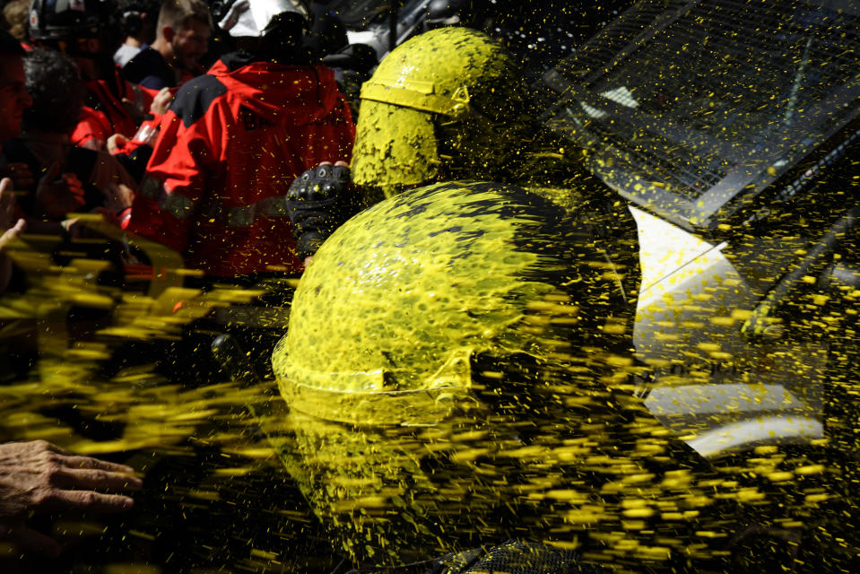 Pro independence demonstrators throw paint at Catalan police officers during clashes in Barcelona, Spain, on Saturday, Sept. 29, 2018. Catalan separatists clashed with police on Saturday in downtown Barcelona as tensions increase before the anniversary of the Spanish region's illegal referendum on secession that ended in violent raids by security forces. (AP Photo/Daniel Cole)