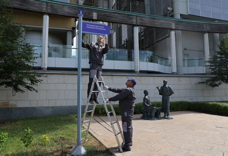 Workers install a direction sign "Luhansk People's Republic Square" in front of the British embassy in Moscow