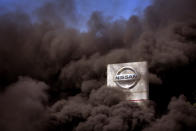 Smoke rises over the Nissan factory as workers burn tires during a protest in Barcelona, Spain, Thursday, May 28, 2020. Japanese carmaker Nissan Motor Co. has decided to close its manufacturing plans in the northeastern Catalonia region, resulting in the loss of some 3,000 direct jobs. (AP Photo/Emilio Morenatti)