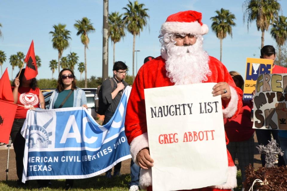 Local organizations in Brownsville, Texas, hold a rally, including a sign saying Gov. Abbott is on Santa's naughty list, before a news conference announcing the governor's signing of three bills broadening border security policies in the state on Monday, Dec. 18, 2023. (AP Photo/Valerie Gonzalez)