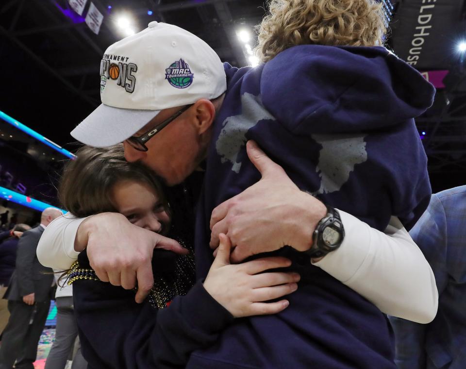 Akron coach John Groce kisses his children after the Zips defeated Kent State in the Mid-American Conference Tournament championship game Saturday in Cleveland.