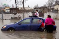 <p>Flint resident Brayden Bend, 5, sits on top of his mother’s friend’s vehicle on Robert T. Longway Boulevard at North Center Road on Tuesday, Feb. 20, 2018, in Flint, Mich. High flood waters caused several motorists to become stuck. (Photo: Bronte Wittpenn/The Flint Journal-MLive.com via AP) </p>