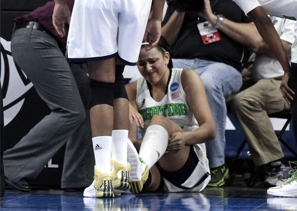 Notre Dame forward Natalie Achonwa is tended to by a trainer in the second half of their NCAA women's college basketball tournament regional final game against Baylor at the Purcell Pavilion in South Bend, Ind., Monday, March 31, 2014. Achonwa left the game with the injury. (AP Photo/Paul Sancya)