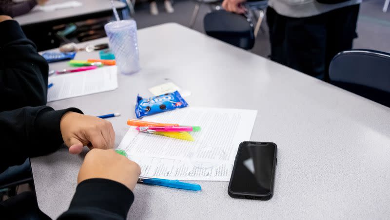 A student has their cellphone out on a table as class begins at Cyprus High School in Magna on Jan. 27, 2023. The school’s policy allows for cellphones and other electronic devices to be used between classes, but they must be put away during class.