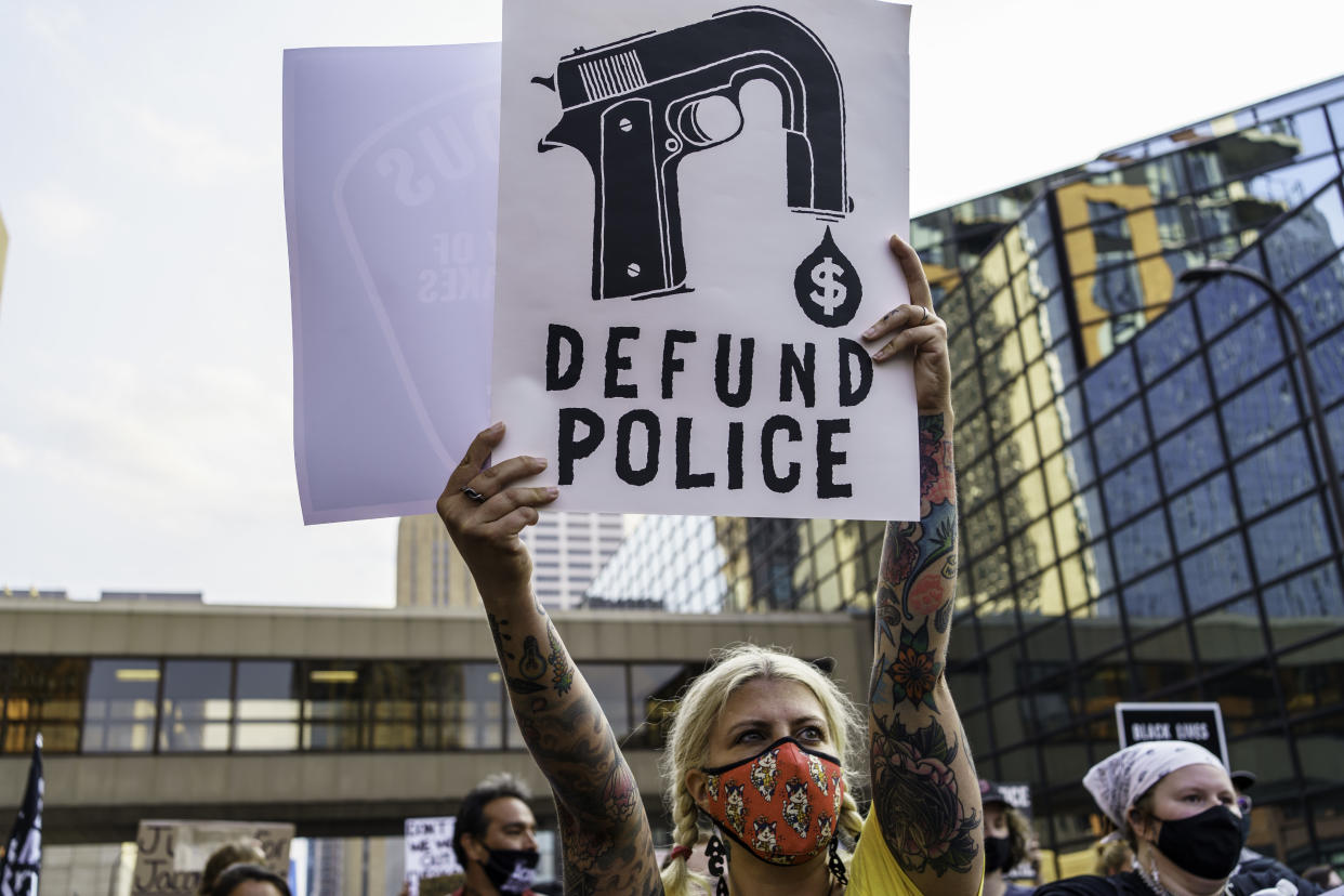 A protester holds a sign reading: Defund police. 