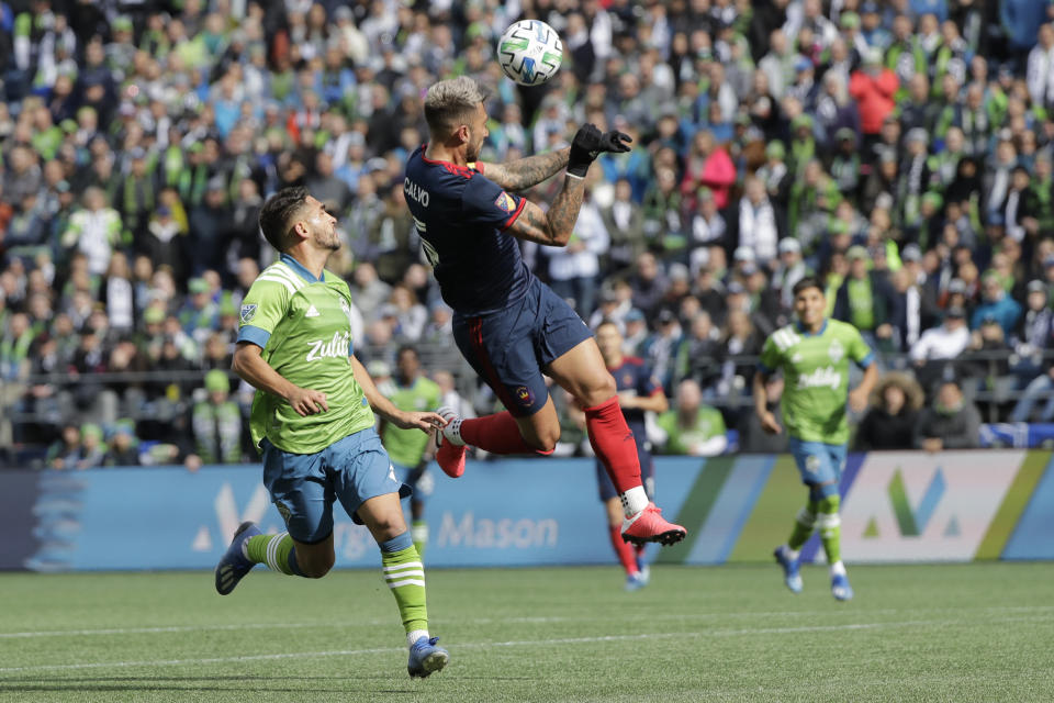 Chicago Fire defender Francisco Calvo, center, heads the ball in front of Seattle Sounders midfielder Cristian Roldan, left, during the first half of an MLS soccer match, Sunday, March 1, 2020, in Seattle. (AP Photo/Ted S. Warren)