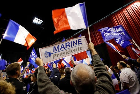 Supporters of Marine Le Pen, French National Front (FN) political party leader and candidate for French 2017 presidential election, hold French flags and posters during a political rally in Perpignan, France, April 15, 2017. REUTERS/Jean-Paul Pelissier