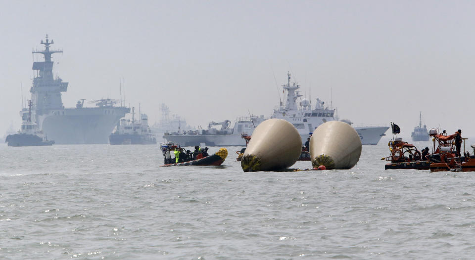 Searchers and divers look for people believed to have been trapped in the sunken ferry boat Sewol near the buoys which were installed to mark the vessel in the water off the southern coast near Jindo, south of Seoul, South Korea, Tuesday, April 22, 2014. One by one, coast guard officers carried the newly arrived bodies covered in white sheets from a boat to a tent on the dock of this island, the first step in identifying a sharply rising number of corpses from the South Korean ferry that sank nearly a week ago. (AP Photo/Lee Jin-man)