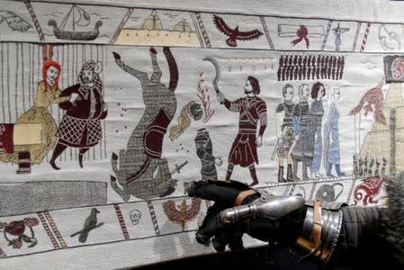 A visitor points at the Game of Thrones Tapestry in Bayeux,