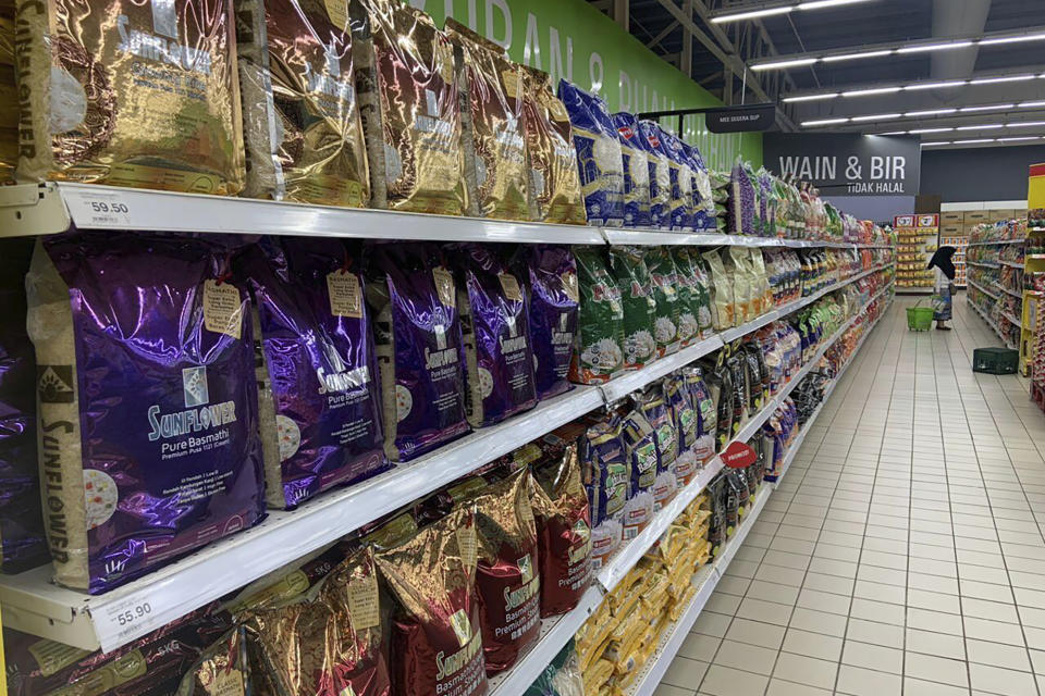 A customer looks at products along an aisle with imported rice in a supermarket in Kuala Lumpur, Malaysia, Tuesday, Oct. 3, 2023. Malaysia's government has reassured the country that enough rice is available and urged people not to hoard locally produced rice after recent panic-buying led to empty shelves in supermarkets and grocery stores nationwide. (AP Photo/Syawalludin Zain)