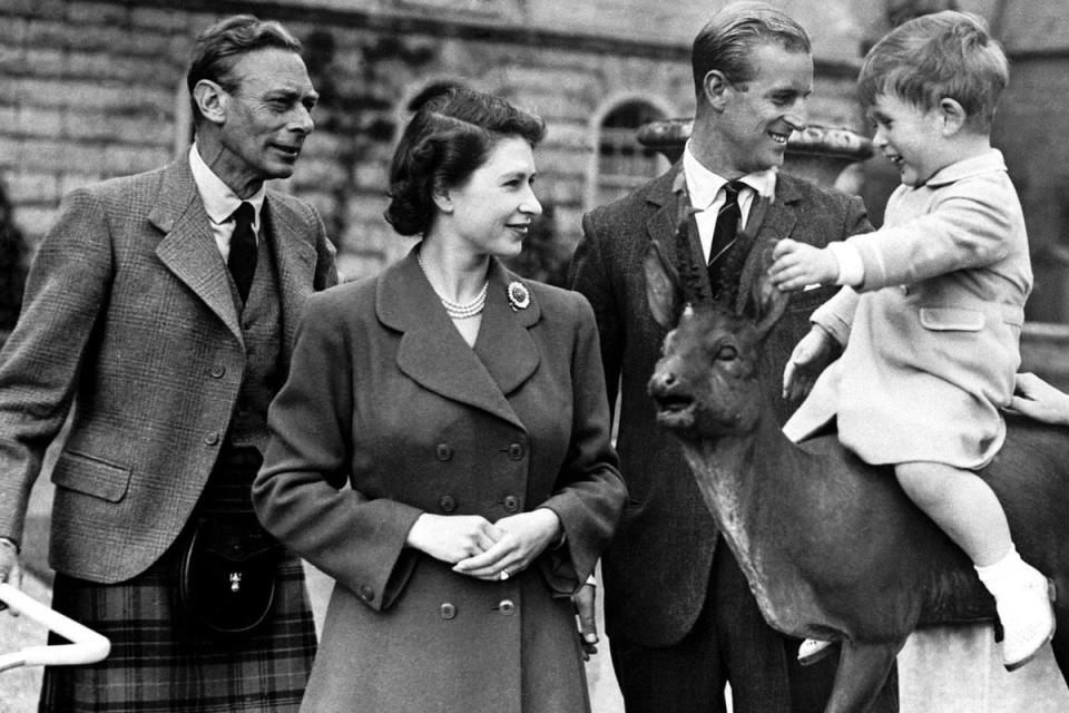 The Queen with her father, King George VI, and Prince Philip watching a young King Charles sitting on a statue at Balmoral in 1951 (PA) (PA Media)