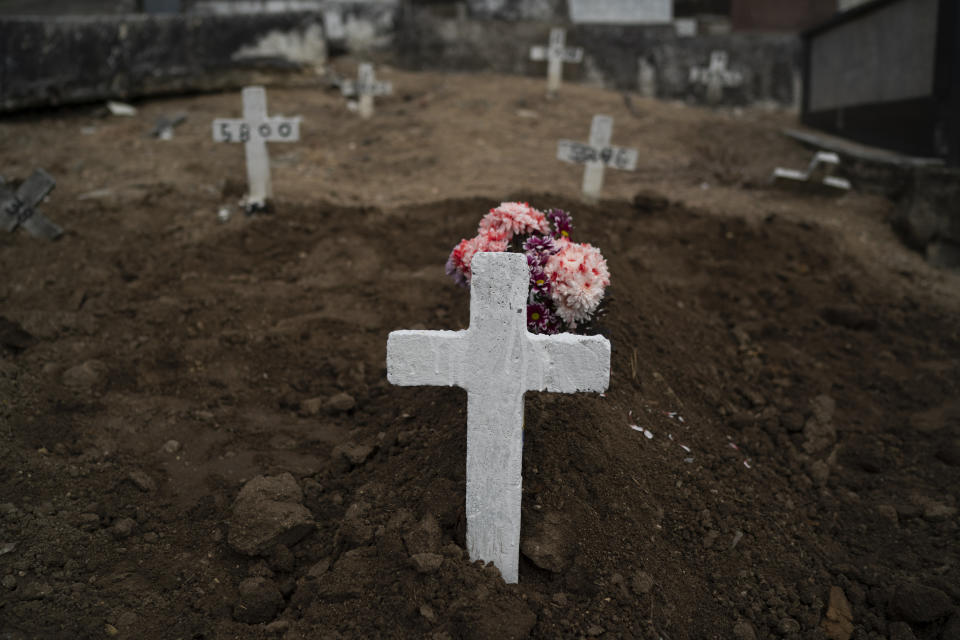 A cross marks the grave of Ana Maria, a 56-year-old nursing assistant who died from the new coronavirus, in Rio de Janeiro, Brazil, Tuesday, April 28, 2020. Ana Maria's daughter Taina dos Santos said that the situation in the Salgado Filho public hospital where her mother worked is complicated and that some health workers have to buy their own protective gear. "She gave everything to her job until the very end," said the 27-year-old daughter. (AP Photo/Leo Correa)