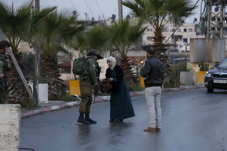 Israeli soldiers check a Palestinian woman at a checkpoint at the entrance to the village of Beit Omar near the West Bank city of Hebron December 1, 2015. REUTERS/Baz Ratner