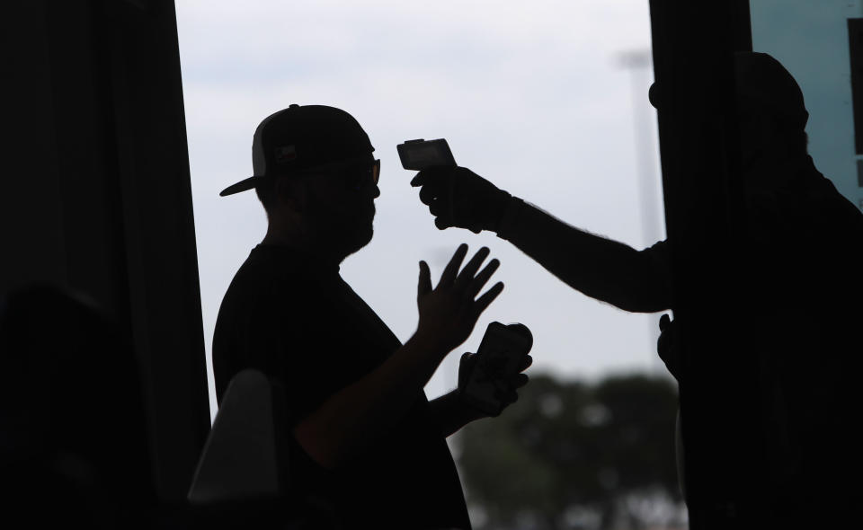 Amid concerns of the spread of the virus that causes COVID-19, a baseball fan has his temperature checked by a security guard before being allowed to tour Globe Life Field, home of the Texas Rangers baseball team in Arlington, Texas, Monday, June 1, 2020. (AP Photo/LM Otero, File)