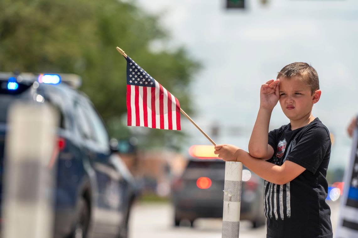 Eight-year-old Will Van Kirk salutes as the funeral procession for North Kansas City police officer Daniel Vasquez passes by on Wednesday in North Kansas City.
