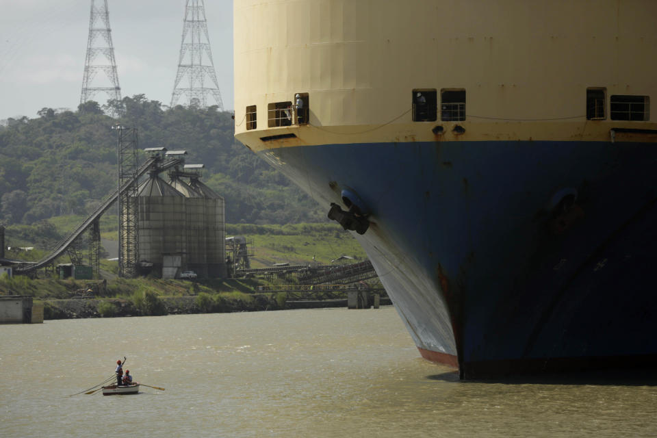 In this Jan. 14, 2014 photo, a small boat takes in a line of rope from a cargo ship while entering to the Pedro Miguel locks at the Panama Canal near Panama City. The current canal expansion project would double its capacity. (AP Photo/Arnulfo Franco)